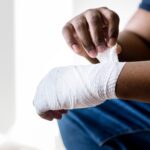 man wrapping injured hand with gauze tape
